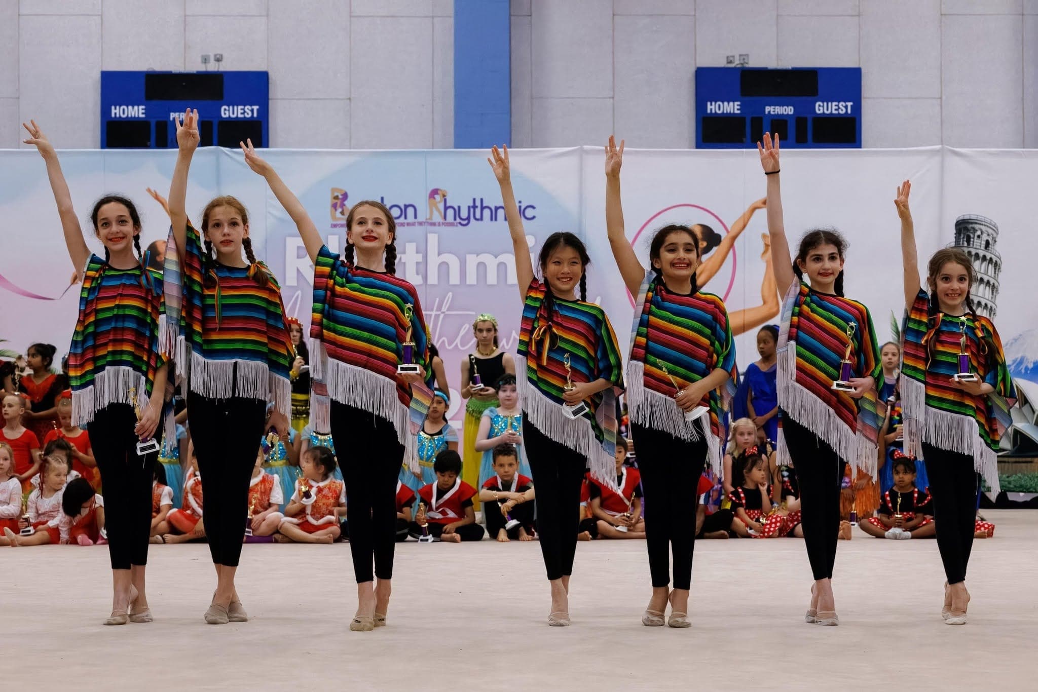 Campers in colorful country-themed costumes holding trophies at a Boston Rhythmic showcase