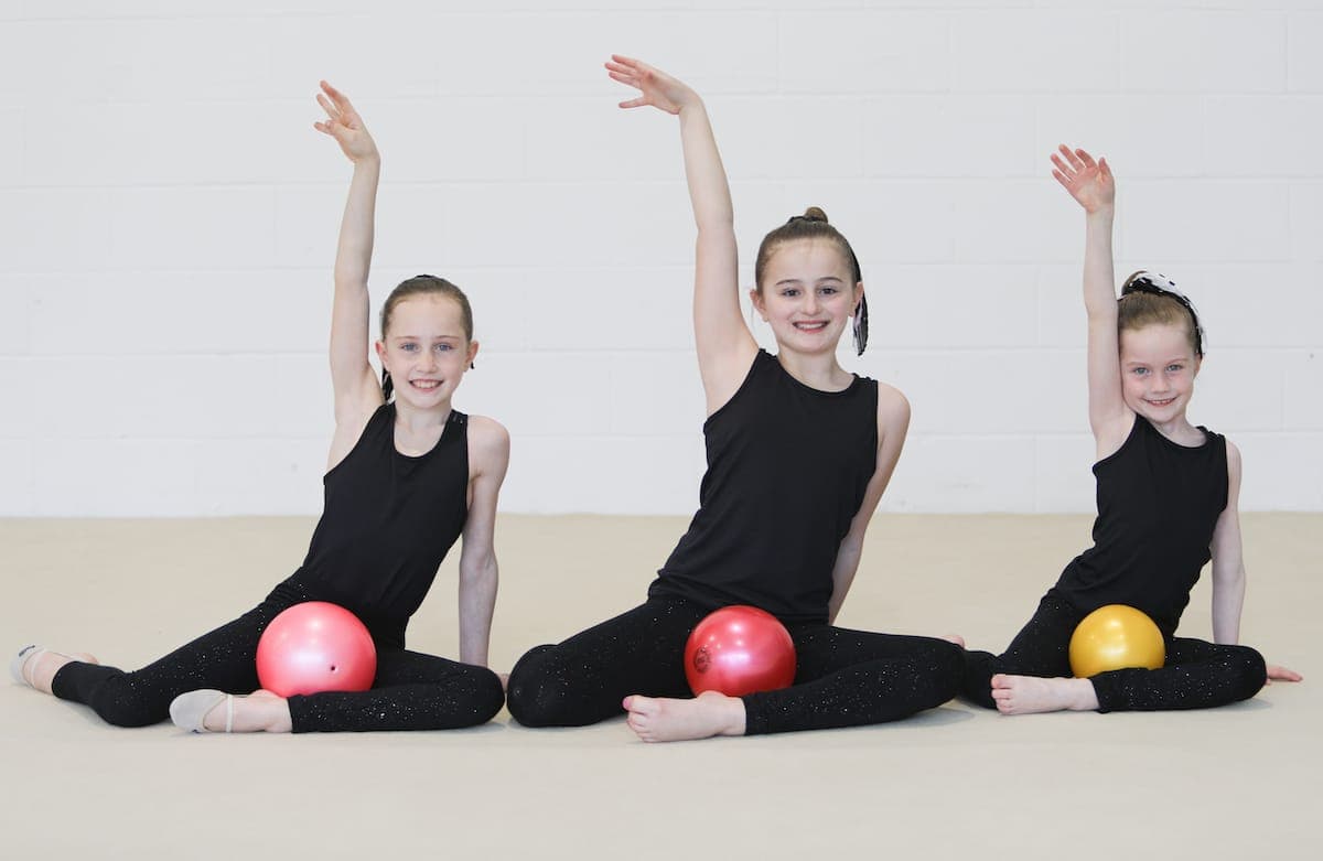 Three campers posing with rhythmic gymnastics balls during a performance
